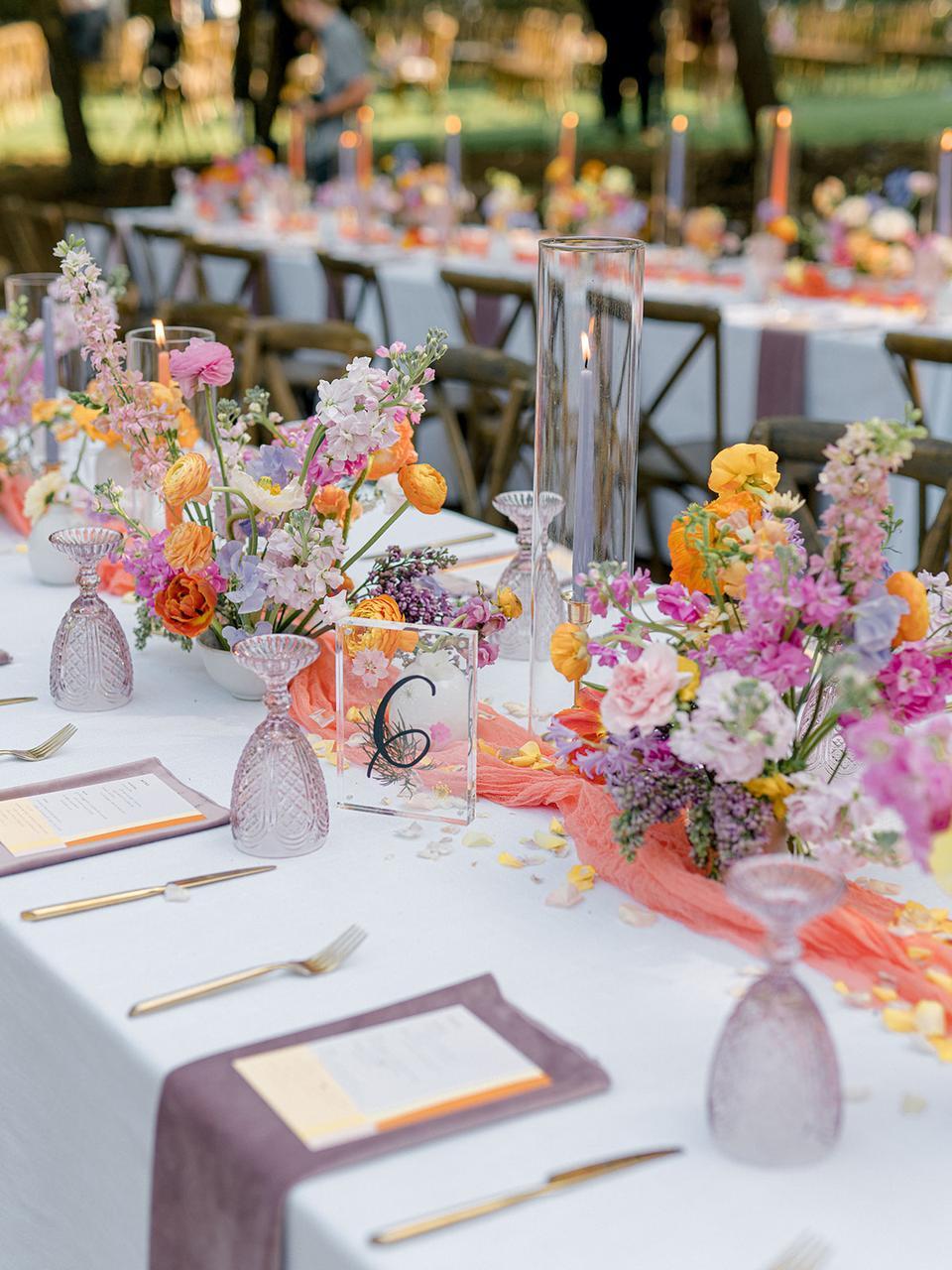 trendy wedding flower idea for 2022 reception tablescape with low centerpieces and bright colors: orange, purple, peach