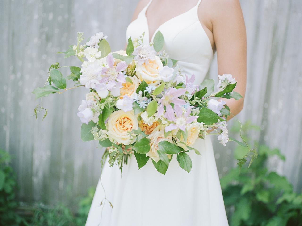 garden style wedding bouquet with pale yellow roses, clematis, white scabiosa, greenery vines