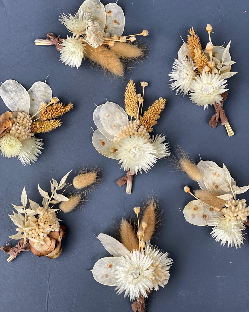 overhead shot of dried floral wedding boutonnieres made from lunaria, ruscus, bunny tails