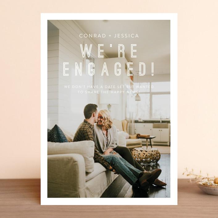 Personalized photo background with white border and 'We're engaged!' in playful type